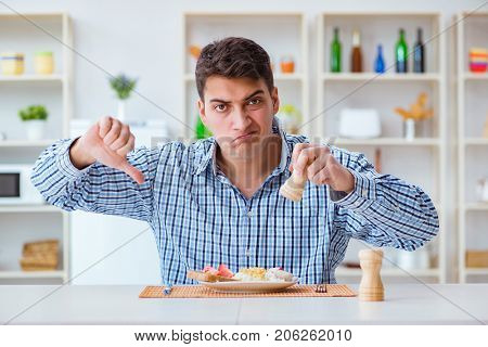 Young husband eating tasteless food at home for lunch