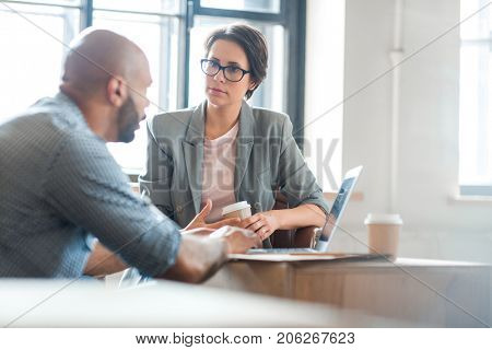 Serious woman listening to co-worker explaining new online business trends