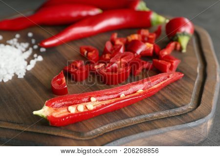 Red chili peppers and sea salt on wooden board, closeup