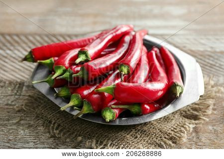 Plate with red chili peppers on wooden table