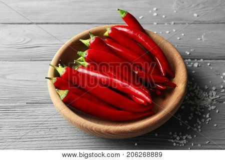 Plate with red chili peppers on wooden table