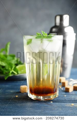 Glass with mint julep on wooden table