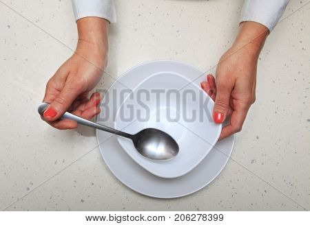 hands of woman who holds spoon and plate