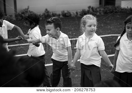 Group of diverse kindergarten students standing holding hands together