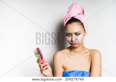 A woman looks sad at herself in the mirror, bad skin, problems, pimples. Mask under the eyes