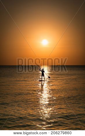 Silhouette of man standing up at paddle Board on sunset, White beach, Boracay. Philiphines.