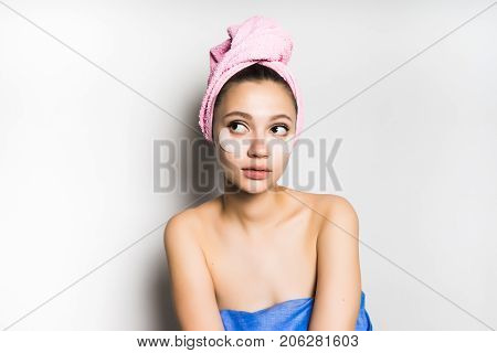A girl with a gel mask under the eyes looks to the left