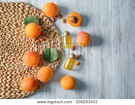 Bottles of apricot oil with fresh fruit and kernels on wooden table