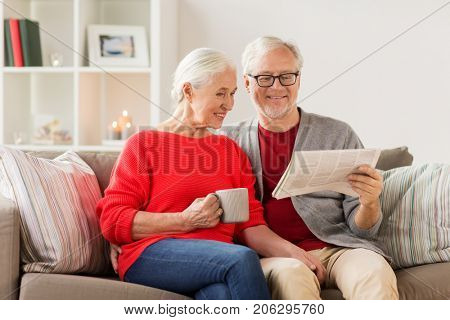 christmas, mass media and people concept - happy smiling senior couple reading newspaper at home