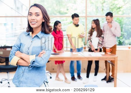 Portrait of young Asian woman looking at camera with self-confidence and determination as member of a young creative team