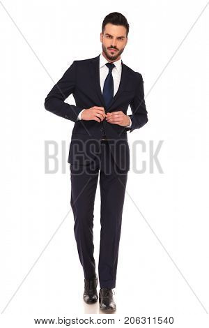 sexy young business man buttoning suit while walking on white background