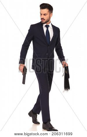 serious young hitman walking and looking back over his shoulder on white background