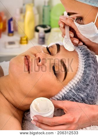 Collagen facial mask for skin treatment. Face of woman of elderly woman 50-60 years old receiving cosmetic procedure in beauty salon close up. Professional beautician. Face cream, homemade.