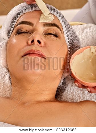Collagen face mask. Facial skin treatment. Face of woman of elderly woman 50-60 years old receiving cosmetic procedure in beauty salon close up . Professional beautician. Healing clay against wrinkles