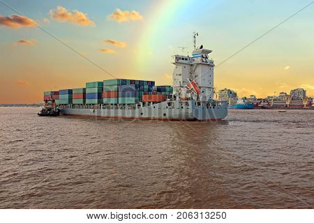 Containership on the Yangon river near Yangon in Myanmar at sunset