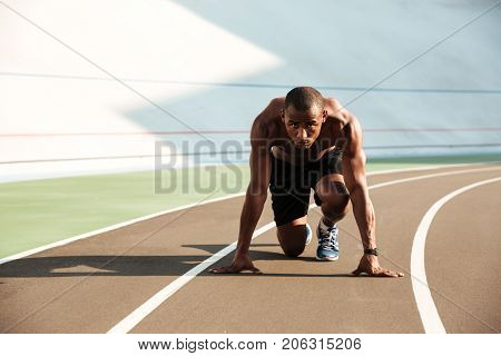 Portrait of a fit athletic afro american sportsman about to start his run on a track field outdoors