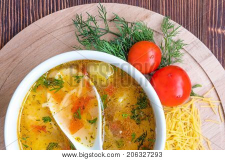 White soup noodles with tomatoes. Potatoes, dill, spices. On a wooden Board.