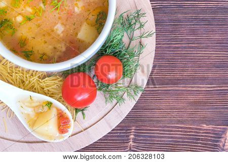 White soup noodles with tomatoes. Potatoes, dill, spices. On a wooden Board.