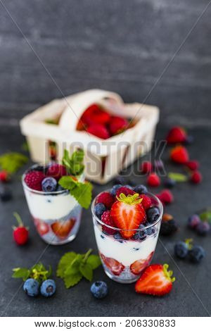 Yogurt with fresh berries fruit and chia seeds on dark background.