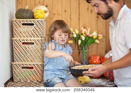 Caucasian family of single father and child cooking apple pie in the kitchen family leisure time homemade baking. Adult teaches little kid how to cook.