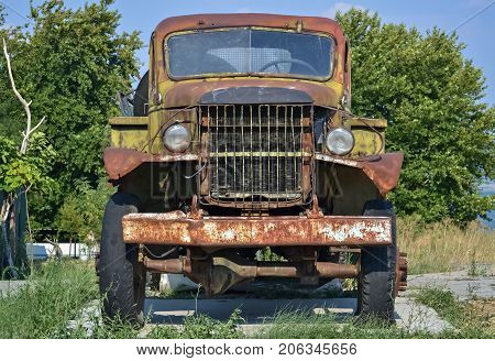 Front part of an old-fashioned rotting truck in the yard