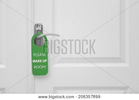 Closed door with sign PLEASE MAKE UP ROOM on handle at hotel