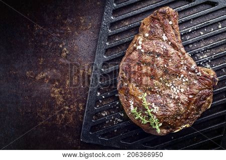 Barbecue dry aged Rib of Beef with salt and pepper as top view on a grillage