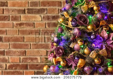 Decorated Christmas tree against brick wall with copy space