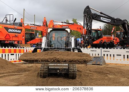 HYVINKAA FINLAND - SEPTEMBER 8 2017: Operator sifts sand with land leveler mounted on Bobcat T450 Compact Track Loader on a sand work site on Maxpo 2017.