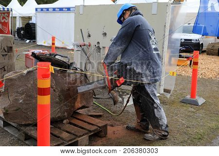 HYVINKAA FINLAND - SEPTEMBER 8 2017: Man saws natural granite stone with ICS chain saw on Maxpo 2017.