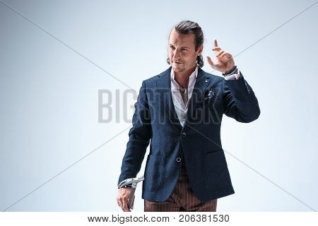 The mature bearded man in a suit holding cane. Isolated on a blue studio background.