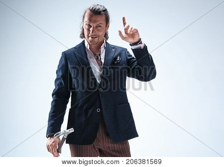 The mature bearded man in a suit holding cane. Isolated on a blue studio background.