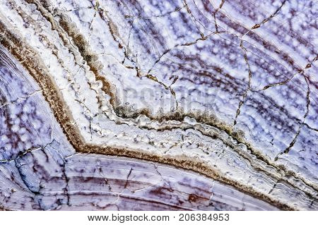 Agate stone texture with cracks, surface of natural unpolished mineral with striped pattern in blue tint, macro shot, abstract background, selective focus