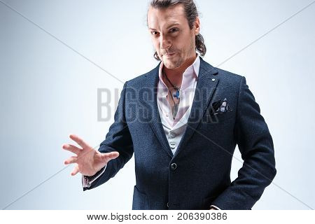 The mature bearded man in a suit holding cane. Isolated on a blue studio background.
