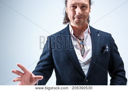 The mature bearded man in a suit holding cane. Isolated on a blue studio background.