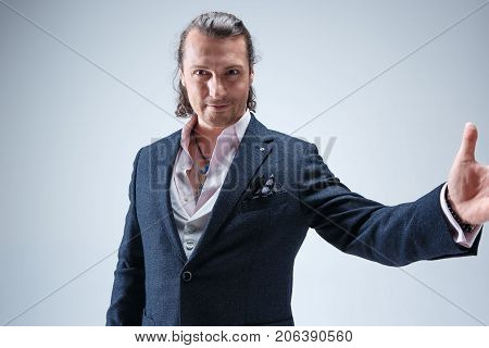 The mature bearded man in a suit holding cane. Isolated on a blue studio background.