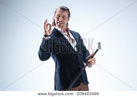 The mature bearded man in a suit holding cane. Isolated on a blue studio background.