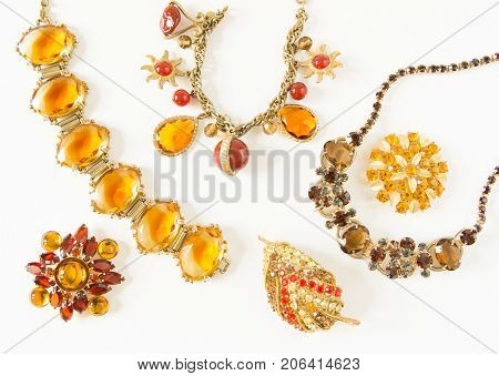 Woman's Jewelry. Vintage jewelry background. Beautiful bright rhinestone brooches, braceletes, necklace and earrings on white. Flat lay, top view.