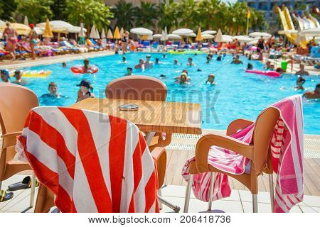 Alanya Turkey - August 14 2017: Tourists are bathing in swimming pool of resort hotel. table near pool with slides. Happy summer vacation. Swimming pool with water park.