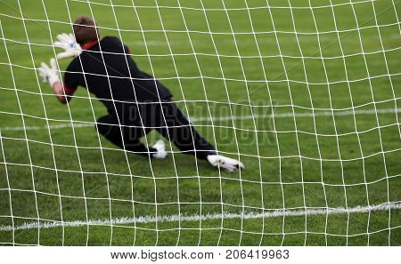 Soccer football goalkeeper making diving save at gate
