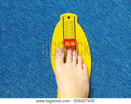 yellow foot measurement device with naked foot upon with measuring tape