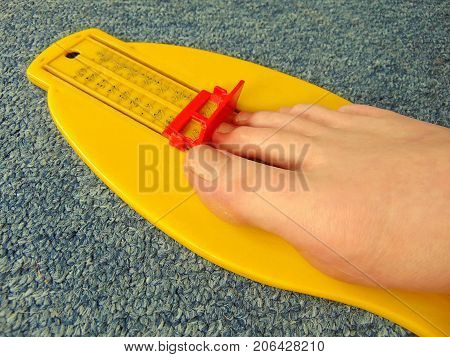 yellow foot measurement device with naked foot upon with measuring tape