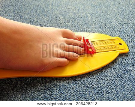 yellow foot measurement device with naked foot upon with measuring tape