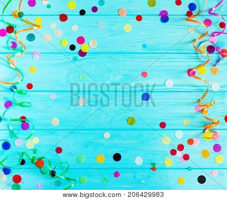 Festive party or carnival confetti on a light blue green wood background with copy space