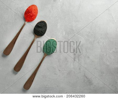 Different colorful superfood powders in spoons on table