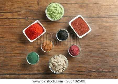 Different colorful superfood powders in bowls on wooden table