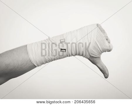 Bad news and information. Medicine aspects. Male hand with bandage showing thumb down sign symbol.