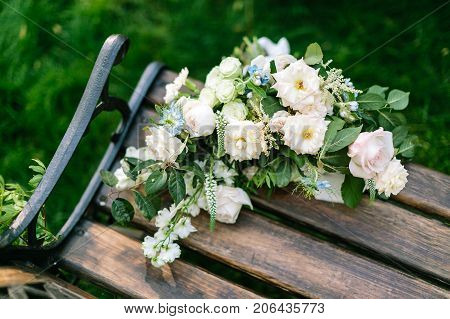floral design, sentiment, present concept. on the bench of park there is forgotten bouquet of marvelous flowers, elegant roses and avalanches in white and light pink shades