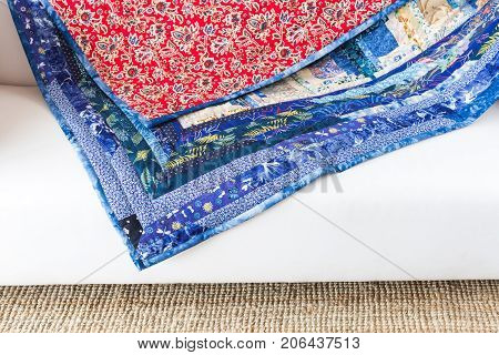 comfort, decoration, art and craft, texture, creativity, patchwork concept - folksy handmaded quilt has two sides, one with geometrical pieces of cloth and other in red color with floral print