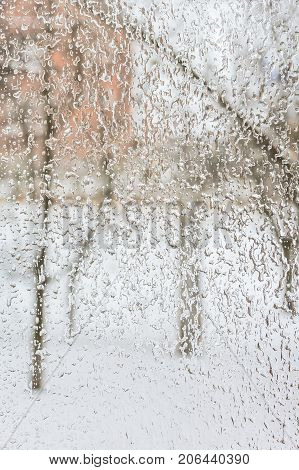 Texture of the ice and drops on the window glass in inclement winter weather close up